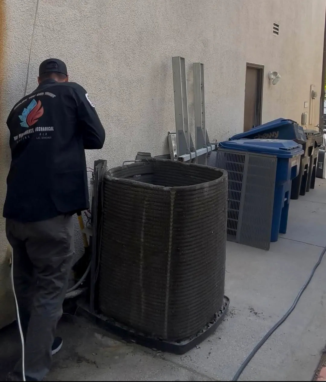 Technician working beside an outdoor air conditioning condenser unit