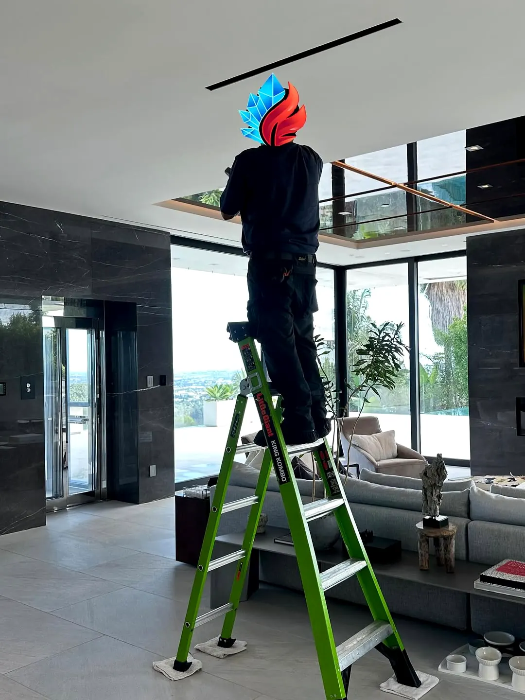 Technician on a ladder installing equipment near the ceiling of a modern home